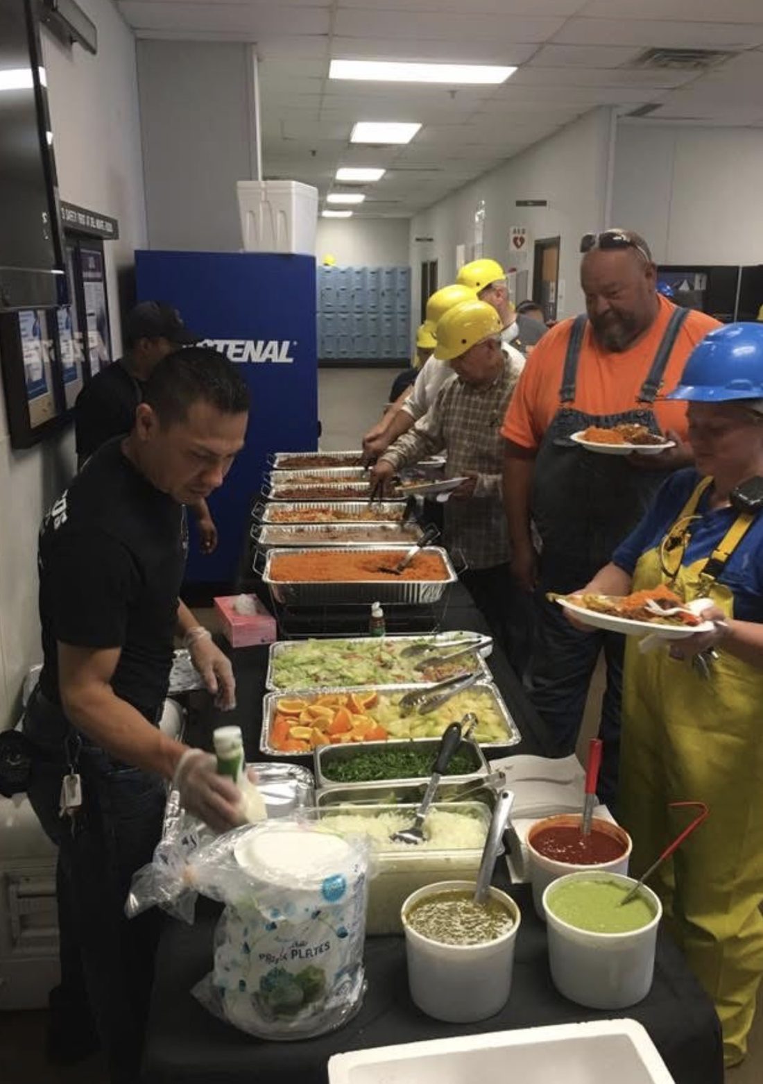 Guests in hard hats going through a Diaz Catering buffet line at a corporate event